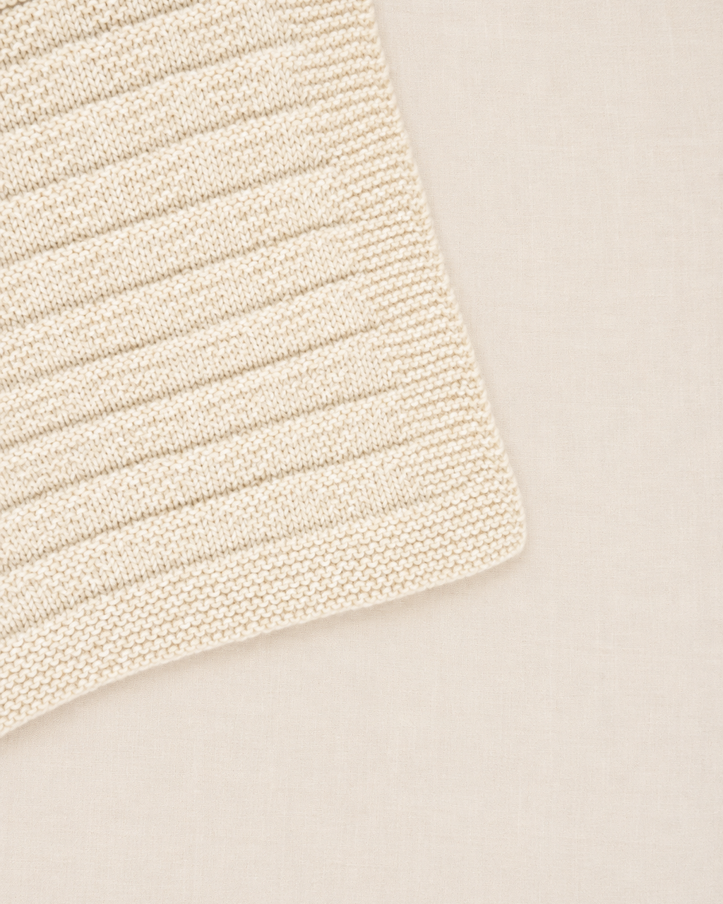 Detalle de la punta de la manta para bebé Clara tejida a mano con patrón de triángulos sutiles Baby Alpaca - Nuna Nina