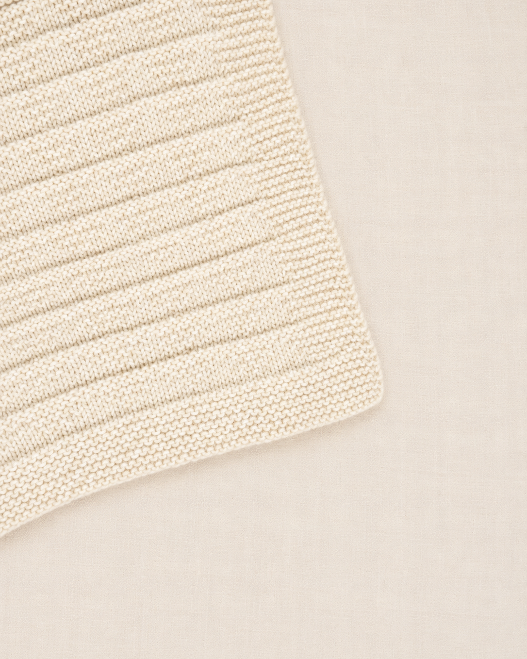 Detalle de la punta de la manta para bebé Clara tejida a mano con patrón de triángulos sutiles Baby Alpaca - Nuna Nina